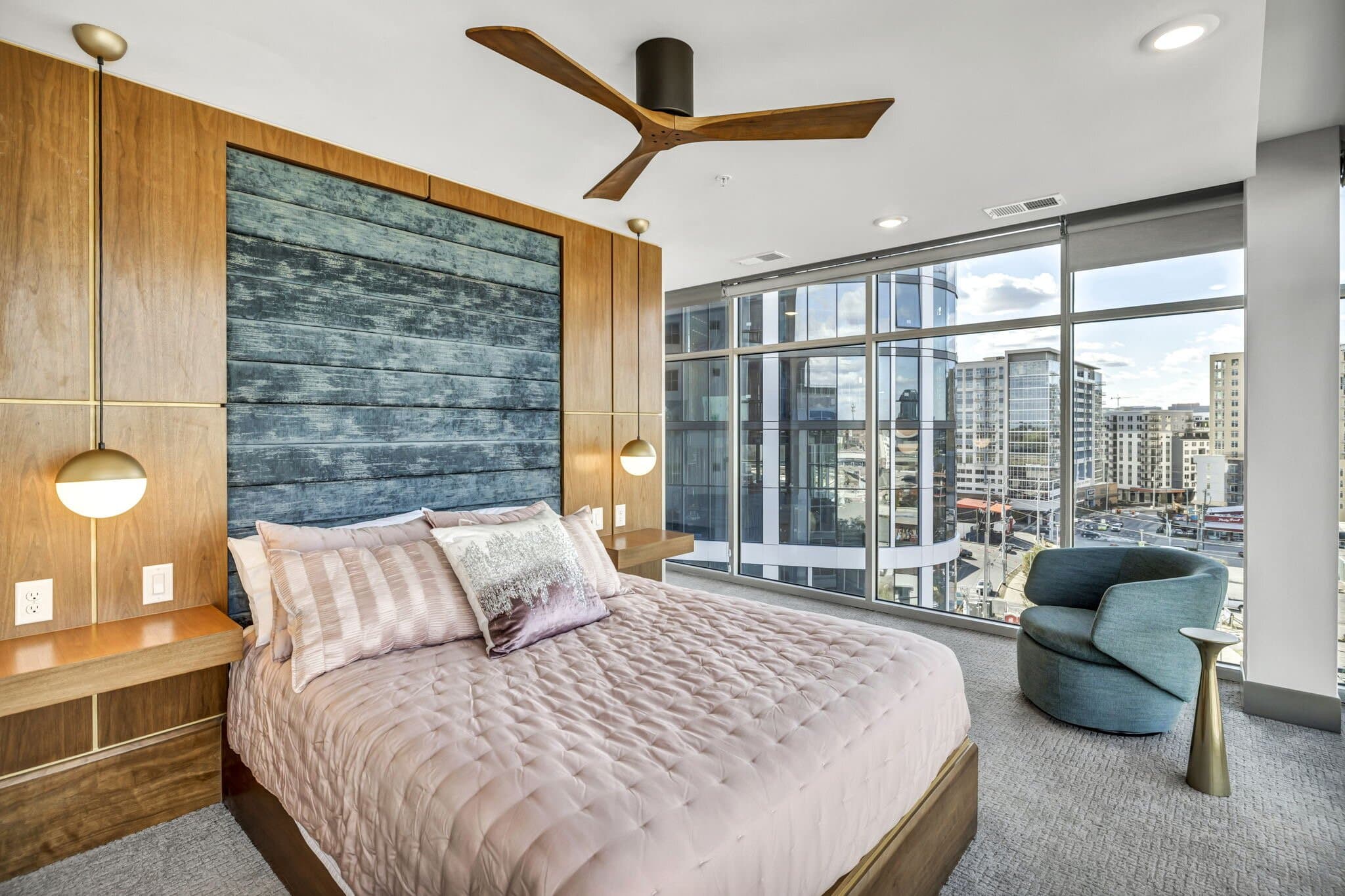 Made-up bedroom at Haven at The Gulch with a wood accent wall, brass sconces, and city views